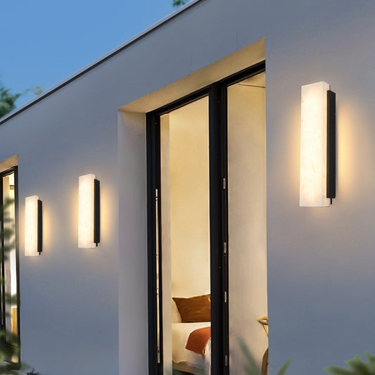 Modern outdoor wall lights on a house exterior with a view into a room.
