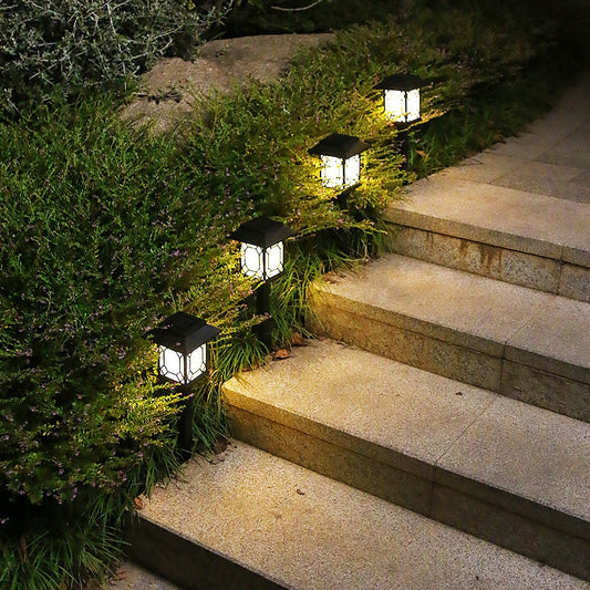 Solar-powered outdoor lights illuminating a set of stone steps surrounded by greenery.