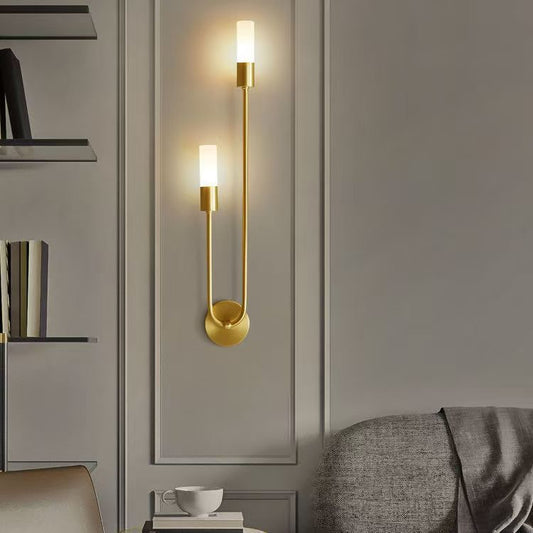 Gold wall sconce on a gray wall with a modern interior setting.