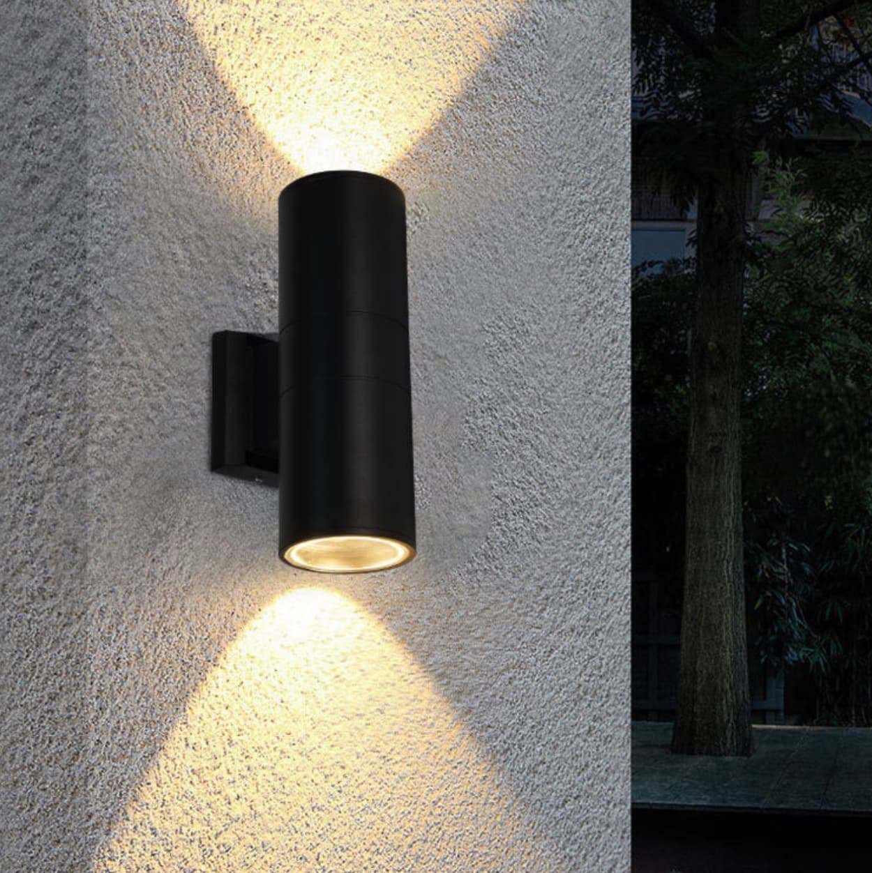 Black outdoor wall light fixture on a textured wall with a dark outdoor setting.