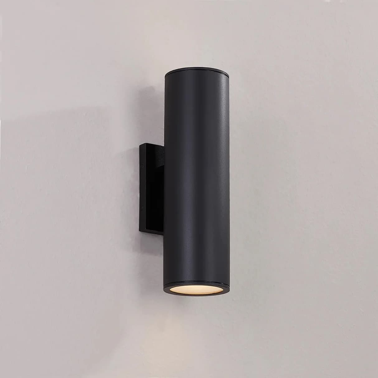 Black cylindrical wall light fixture on a gray background