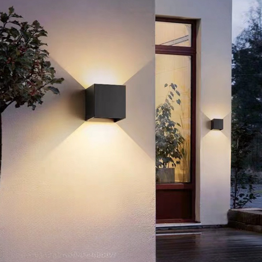 Modern outdoor wall lights on a house exterior with plants and a door.